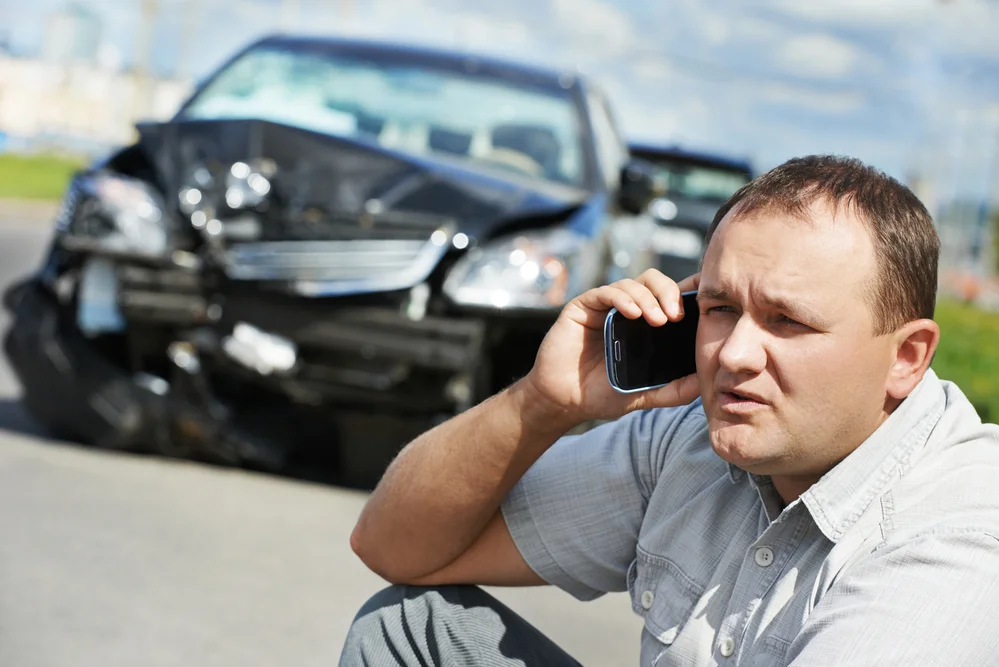 A person talking on a cell phone after a car accident,