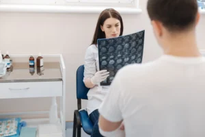 A doctor reviewing MRI scans in front of the patient.